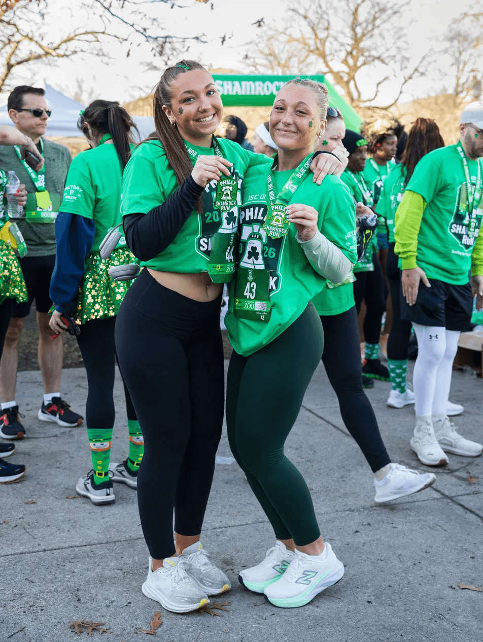 Two Philly Shamrock Run finishers proudly holding their 2026 finisher medals